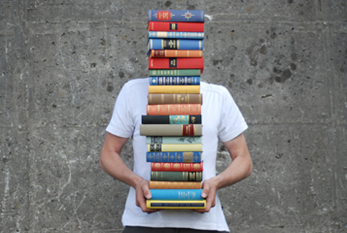 junger Mensch mit einem Bücherstapel