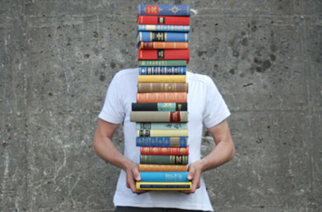 junger Mensch mit einem Bücherstapel